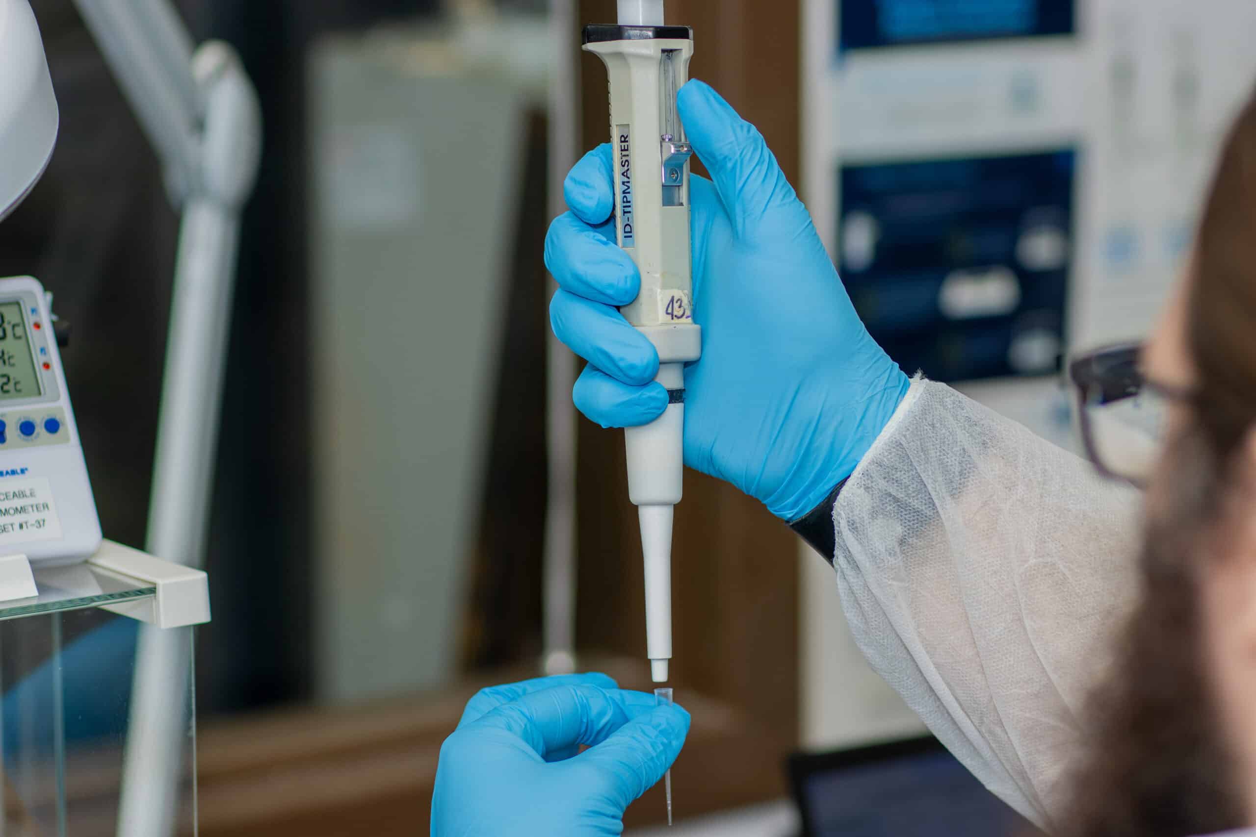 hands with gloves using pipette in laboratory